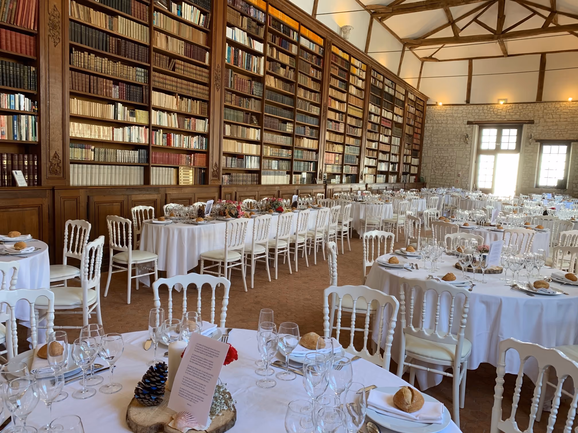 Salle de réception bibliothèque entièrement dressée pour un banquet sous ses rayonnages anciens