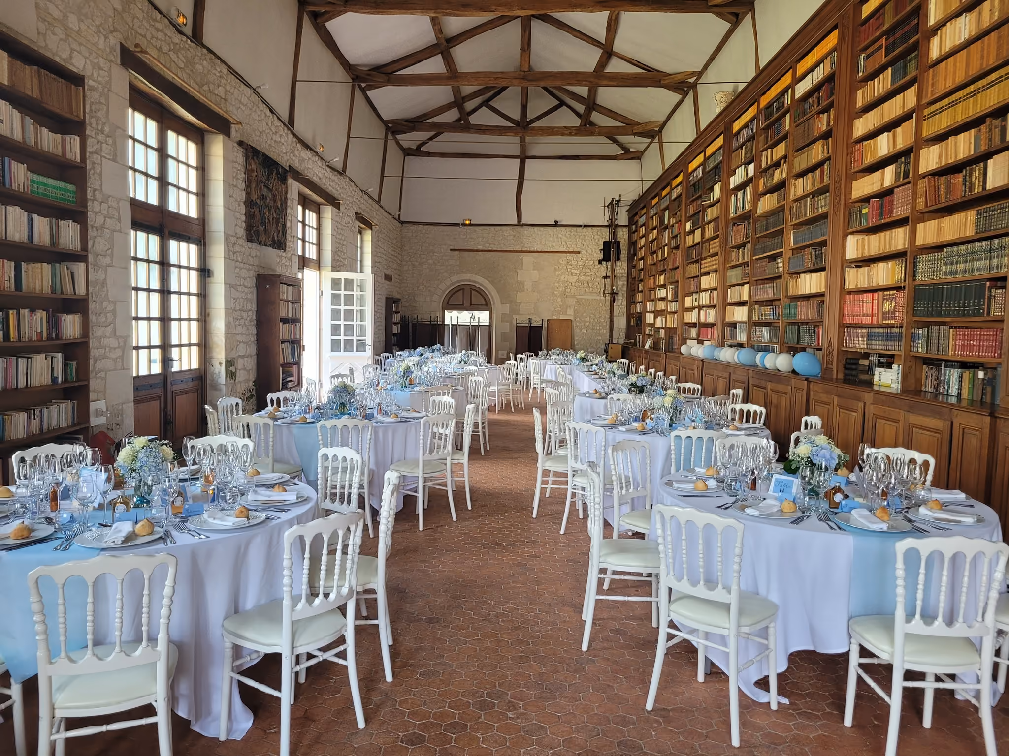 Bibliothèque du château dressée pour un déjeuner avec nappage blanc et décor bleu ciel