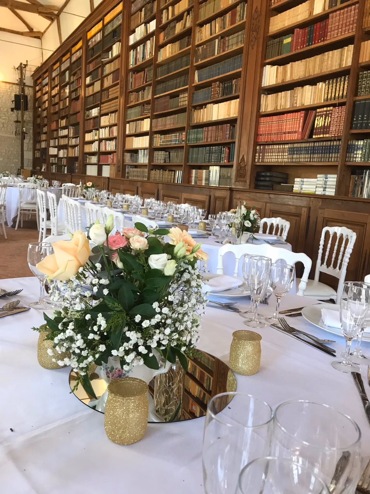 Longues tables dressées en enfilade dans la salle bibliothèque aux rayonnages de livres anciens