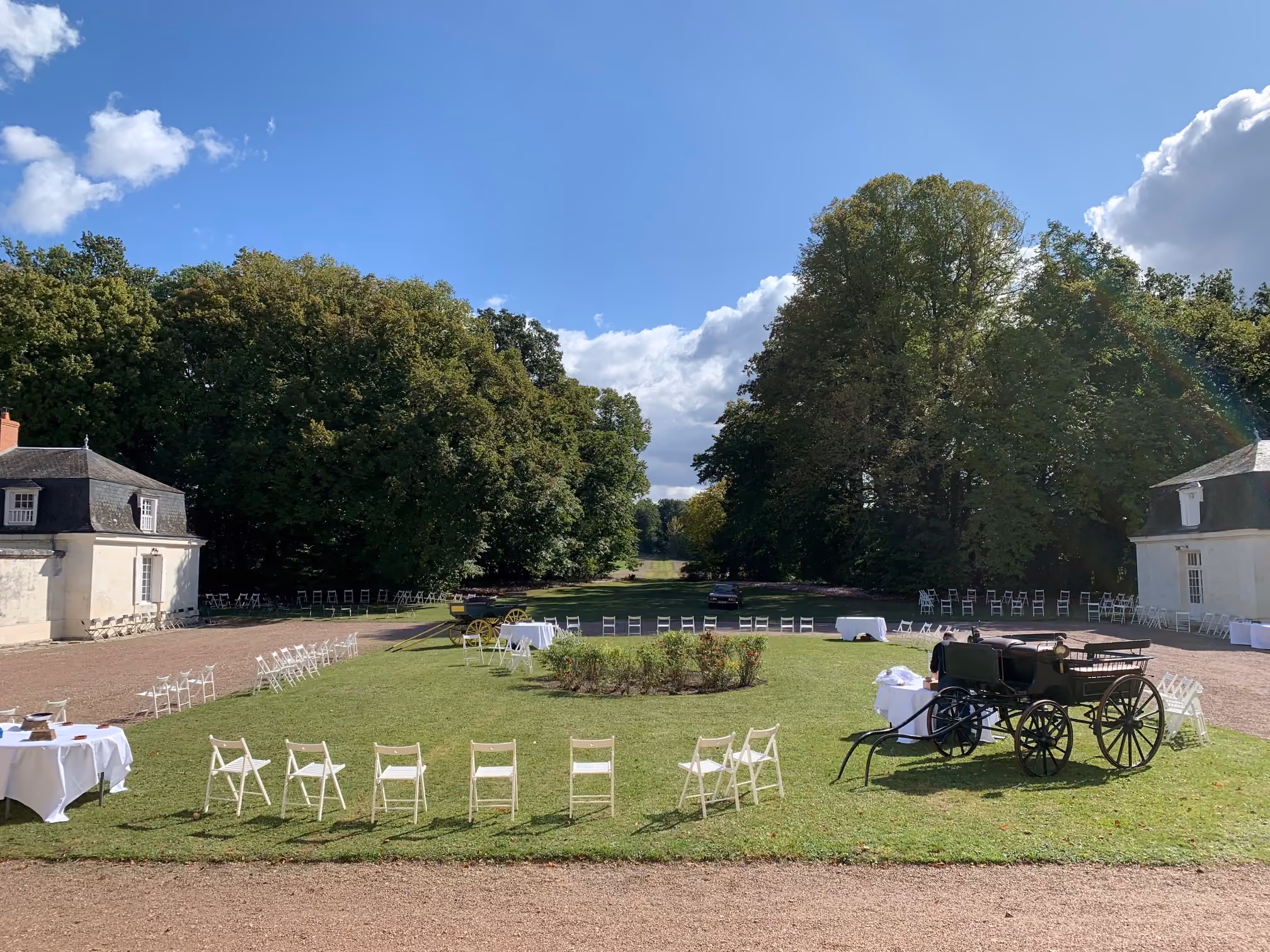 Cour d'honneur préparée pour un cocktail avec chaises blanches en cercle et calèches