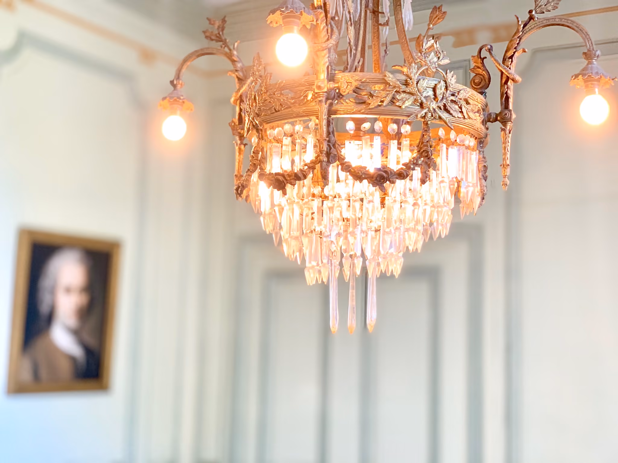 Lustre en bronze doré à pampilles de cristal allumé dans un salon du château