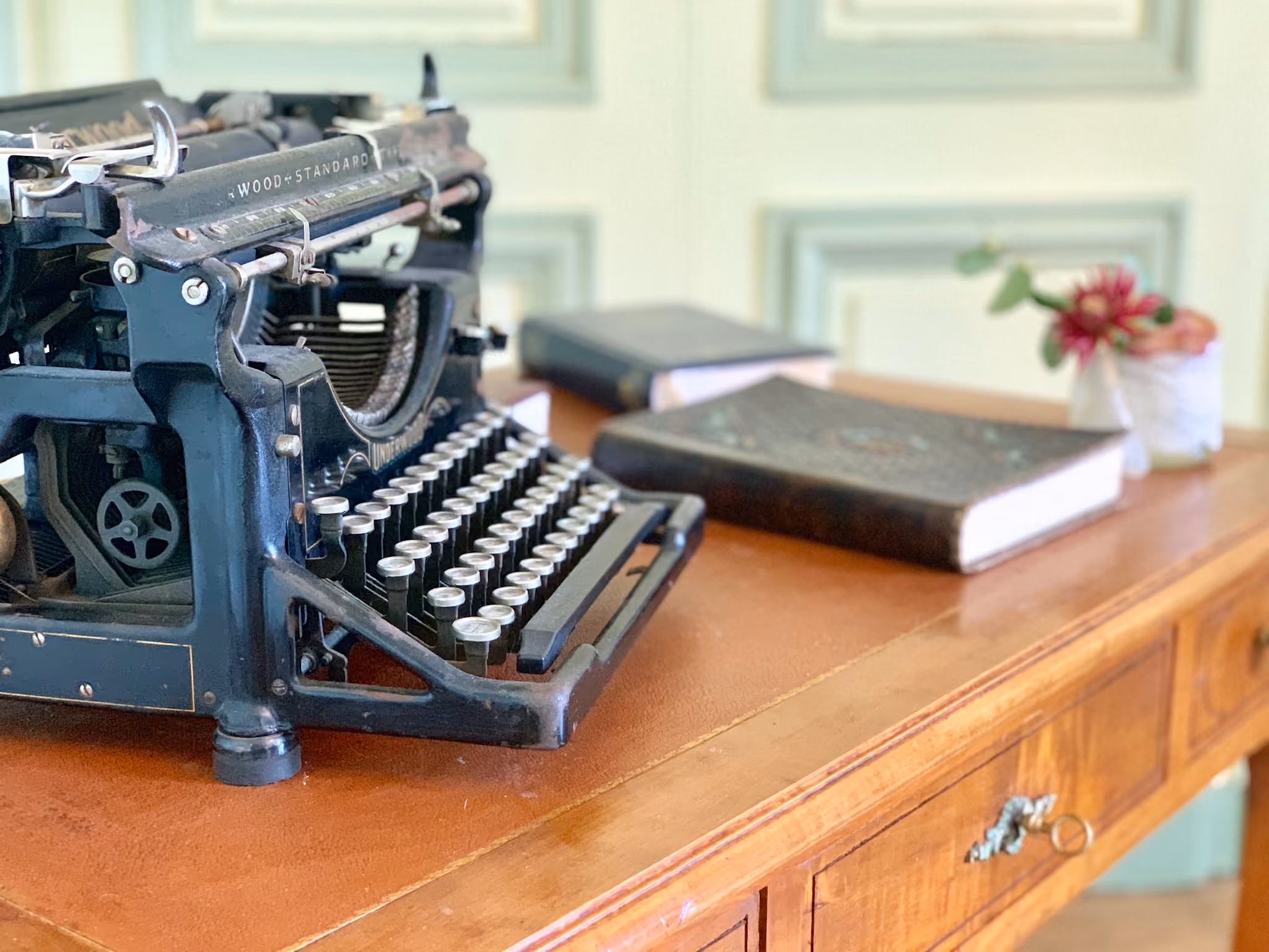 Machine à écrire Underwood ancienne sur un bureau devant des boiseries vert pâle