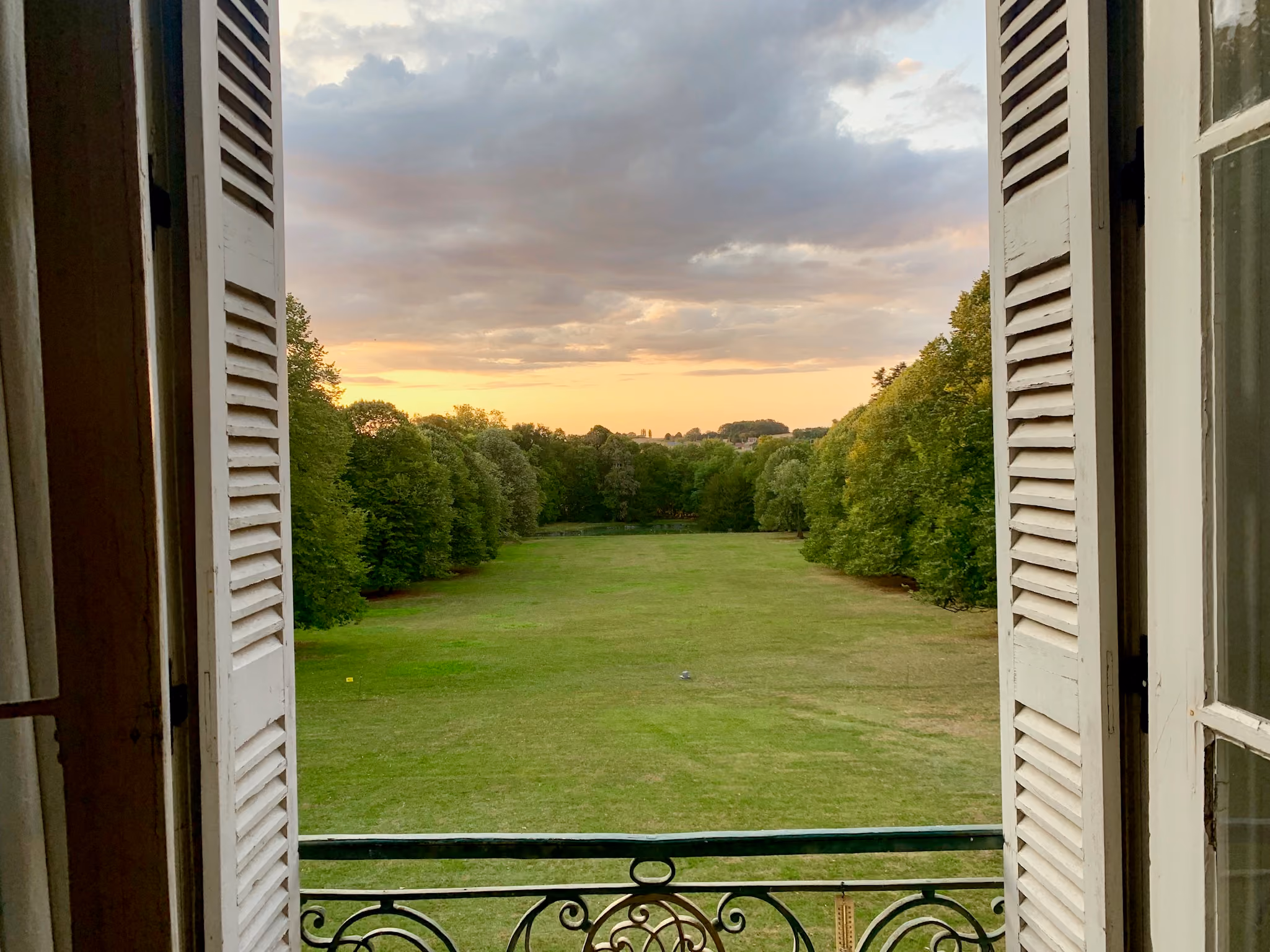 Perspective engazonnée du parc au coucher du soleil vue d'une fenêtre du château