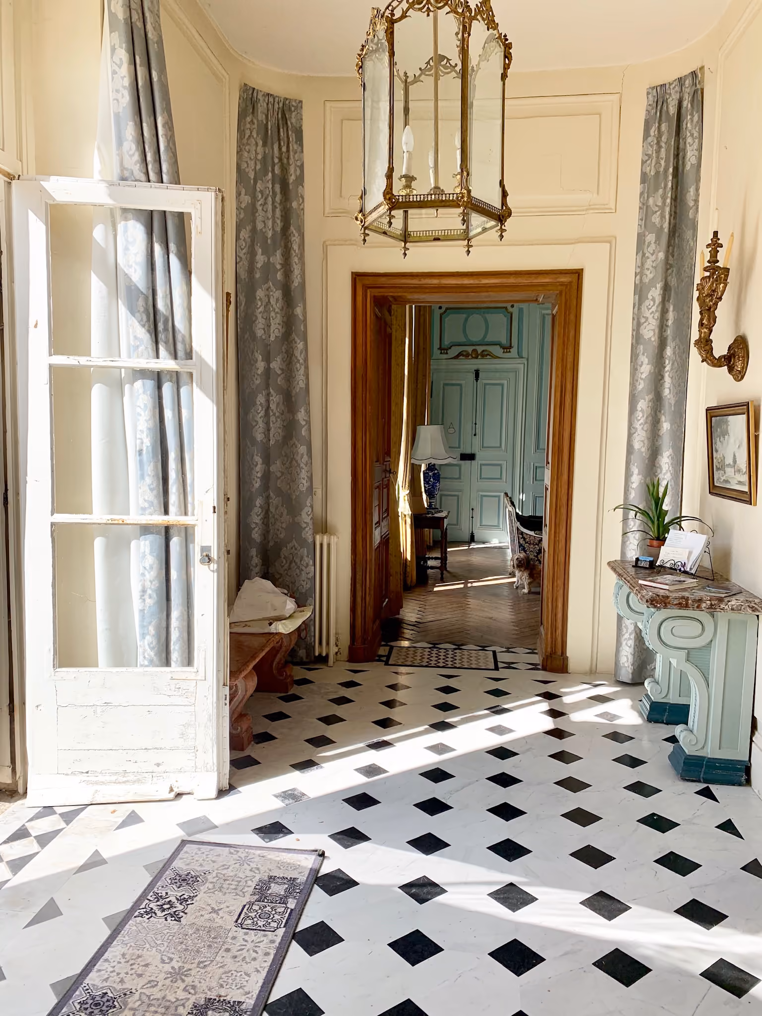 Vestibule au dallage de marbre noir et blanc et lanterne dorée ouvrant sur les salons