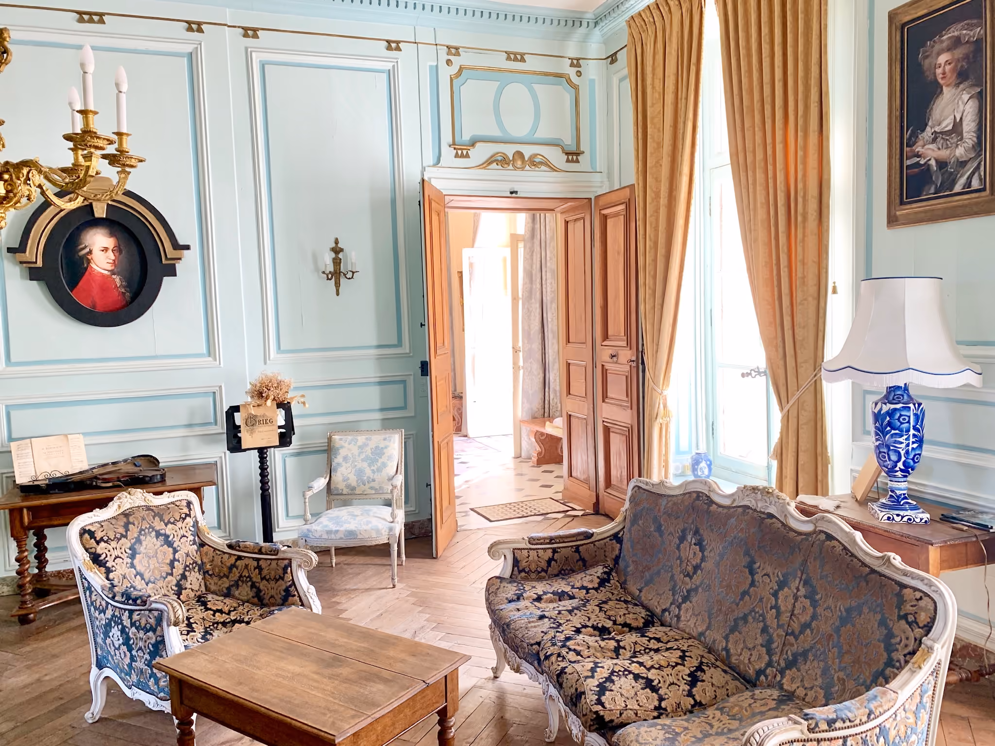 Salon de musique aux boiseries bleu ciel avec médaillon de Mozart et sièges damassés