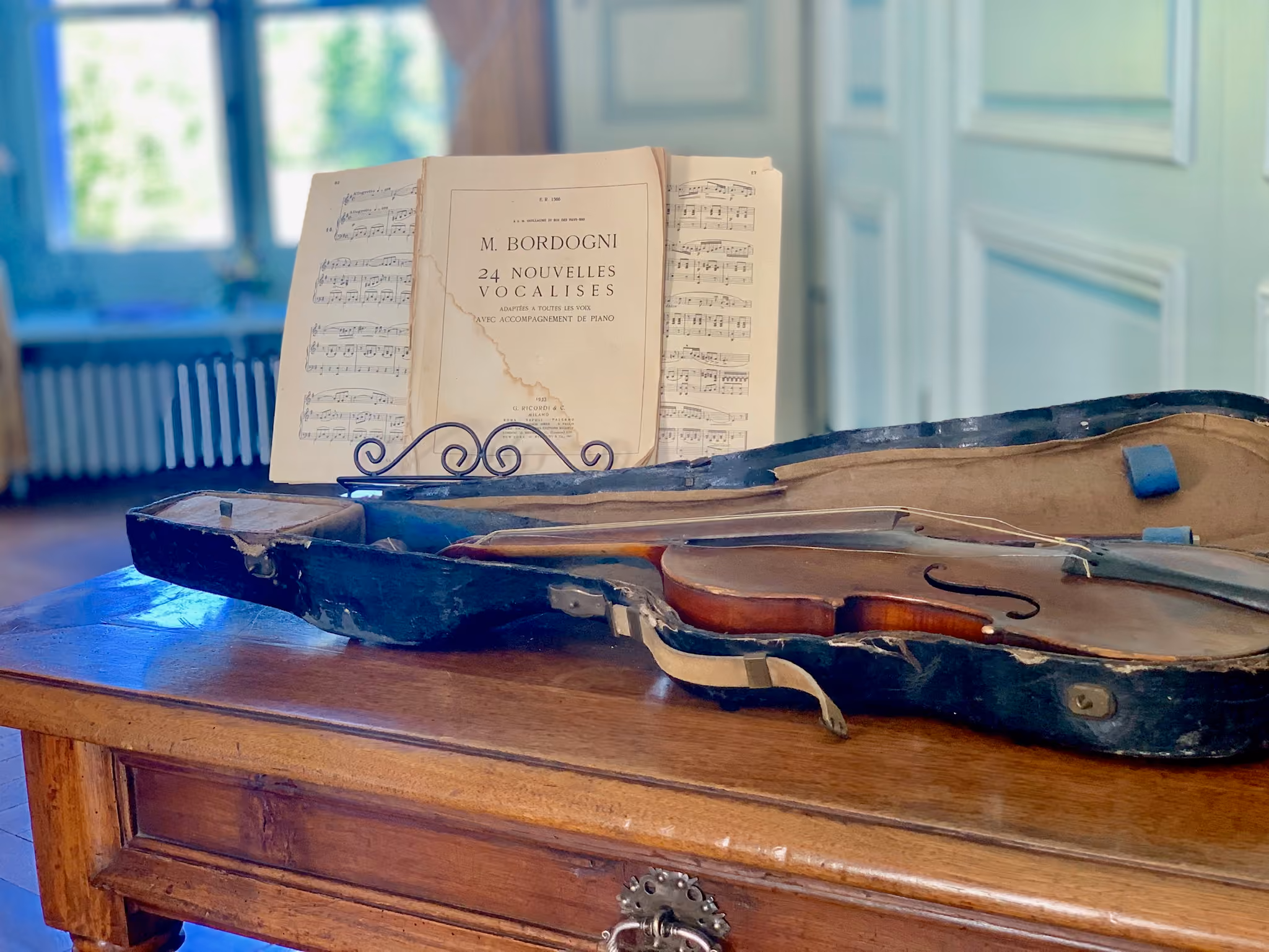 Violon ancien dans son étui et partition de vocalises dans le salon de musique