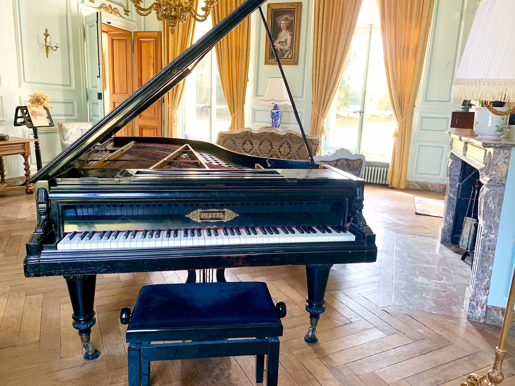 Piano à queue Pleyel ouvert dans le salon de musique aux boiseries bleu ciel
