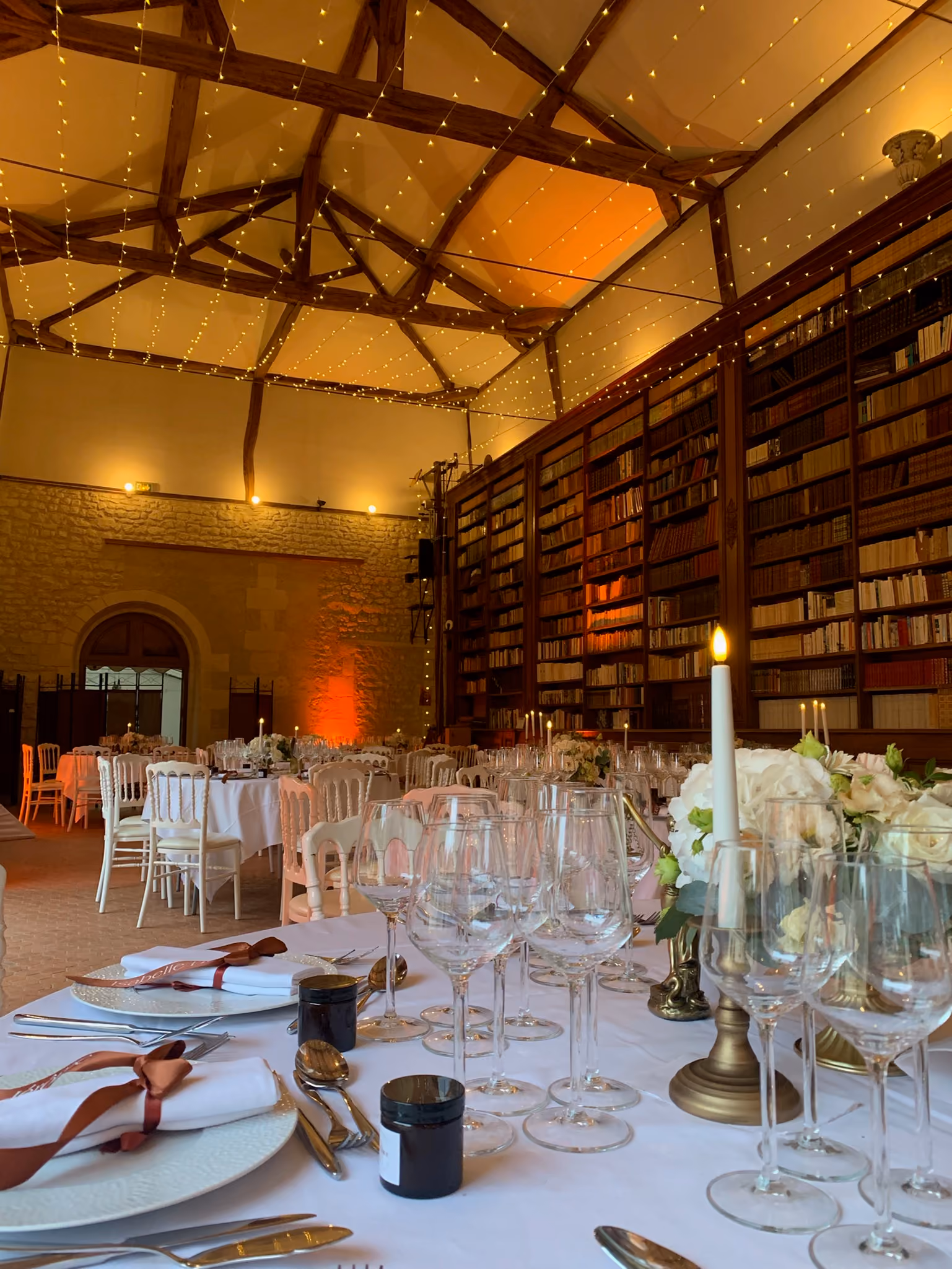 Table dressée aux bougies et hortensias blancs dans la bibliothèque illuminée en soirée